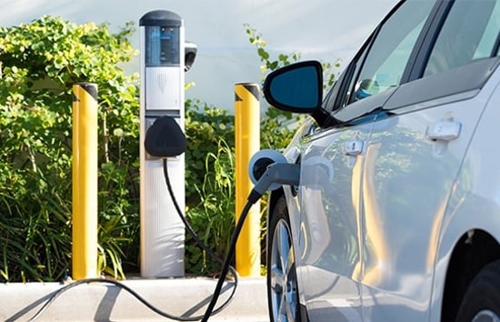 Véhicule électrique blanc en cours de recharge dans un stationnement